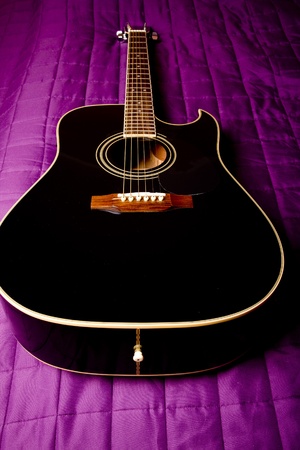  black shiny acoustic guitar  on bedの写真素材
