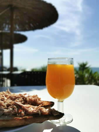 Mediterranean breakfast coffee, juice and tuna sandwich against the backdrop of the seascapeの写真素材
