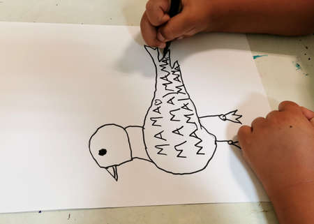 child's hand drawing a bird and writing to mom mamaの写真素材