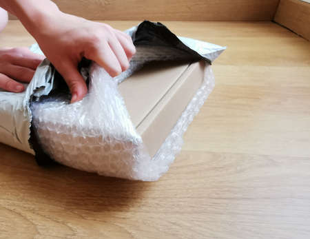 hands open the hears, plastic packaging and cardboard box on the floor of the houseの写真素材