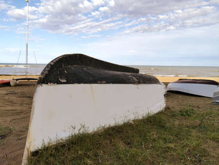 boat upside down lies on the beach amid the seaの写真素材