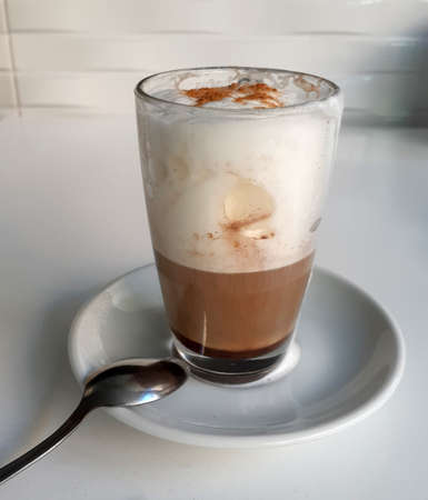 Transparent glass with hot cappuccino in cafe interiorの写真素材