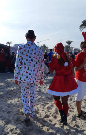 A guy and a girl in Christmas costumes. The guy punches the girl. The young couple is dressed in dresses with a scarf and a Christmas hat.の写真素材