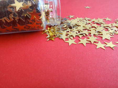 sequin stars on a red background for the New Year's decoration and a copy space in the centerの写真素材