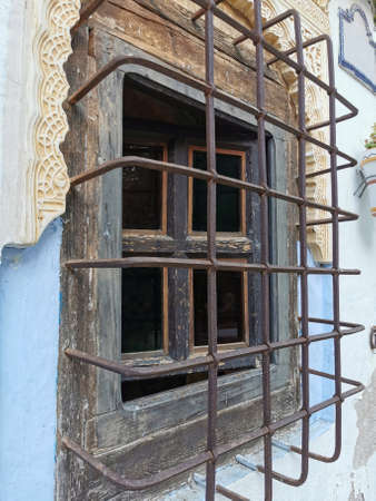 wooden window on the wall of the house with a grate.の写真素材