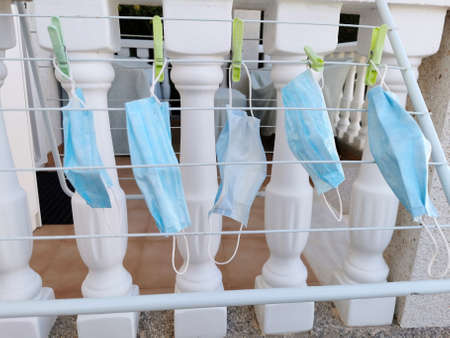 Medical masks hanging dry on round clothes hanger, washing for reuse, disinfecting mask using sunlight after their use, drying on a clothes line, shortage of masks during the Coronavirus, Covid-19 pandemicの写真素材