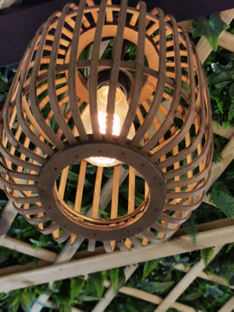 vintage lamp with a wicker lampshade in the background of an ivy gazeboの写真素材
