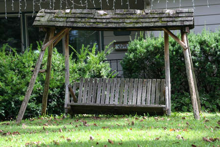 Picture of an old wooden bench with a roof taken on a sunny day.の写真素材