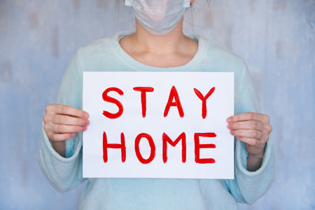 Man holds a poster with a red inscription stay homeの写真素材
