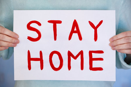 Man holds a poster with a red inscription stay homeの写真素材