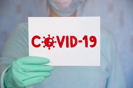 Man holds a poster with a red inscription covid-19の写真素材