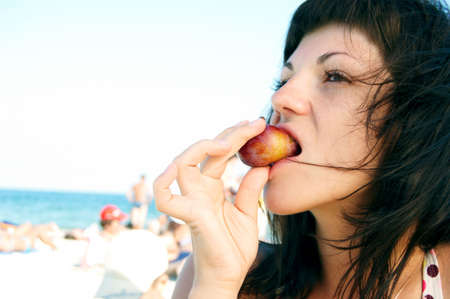woman eats fruit on the beachの写真素材