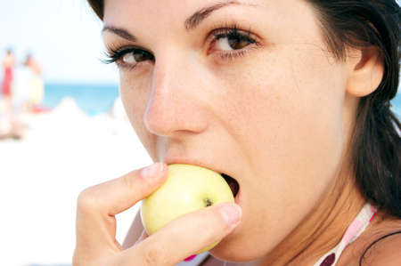 woman eats fruit on the beach