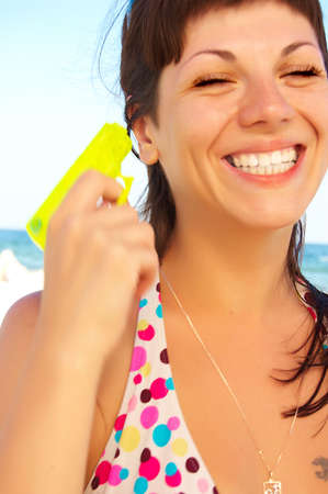 smiling beautiful woman on a beach with yellow toy water gunの写真素材