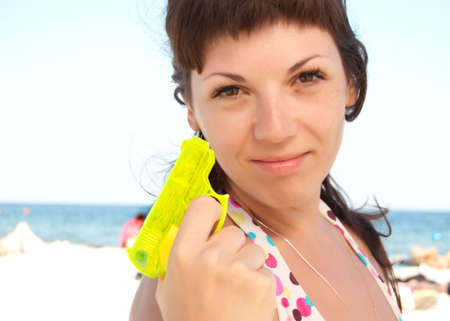 beautiful woman on a beach with yellow toy water gunの写真素材