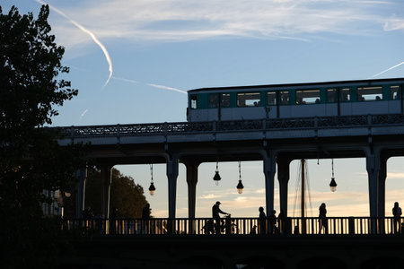 Sunset colors through a bridge in Paris with silhouettes and metro passing by