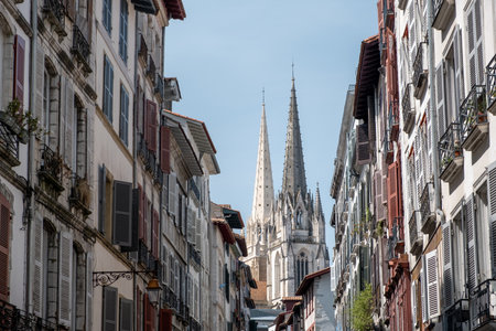 Perspective of traditional facades guiding to Cathedral of Saint Mary of Bayonne with a blue skyの写真素材