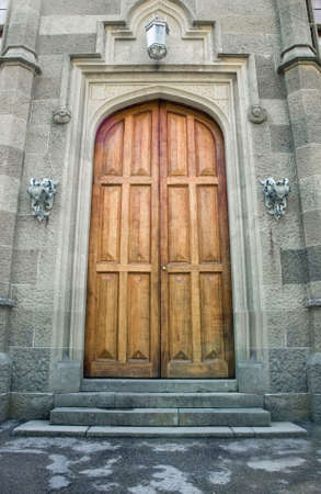 Wooden doors in ancient castle. On each side doors iron holders for torches and lantern. Ancient ornament on walls の写真素材