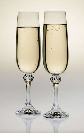 Wine glass with a champagne. A photo on a gleam, it is isolated on a white backgroundの写真素材