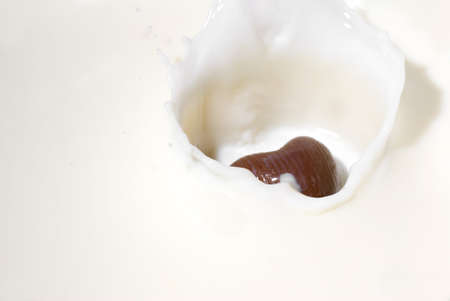 Chocolate heart and milk. Splash in a falling sweet in milkの写真素材