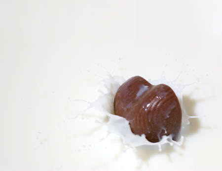 Chocolate heart and milk. Splash in a falling sweet in milkの写真素材
