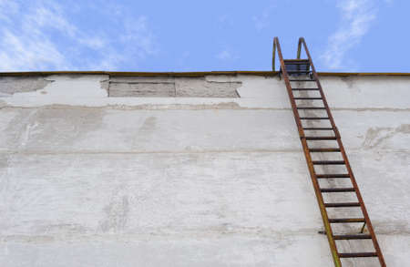 Ladder at a wall. An old, rusty ladder at a concrete wallの写真素材