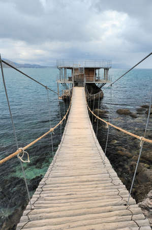 The hinged bridge. Above the sea to island on which it is located by cafeの写真素材