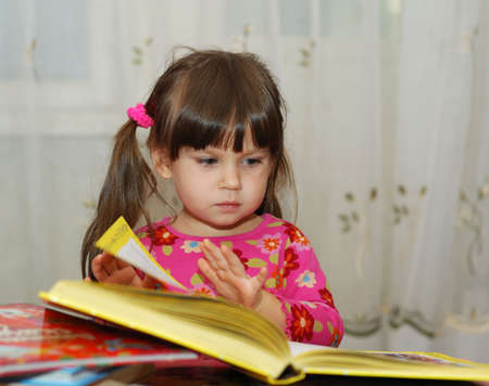 The child reading the book. The three-year girl in house conditionsの写真素材