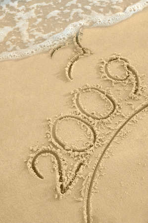 Inscription "2009" on sand. Sea coast with a rolling wave on an inscriptionの写真素材