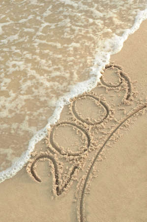 Inscription "2009" on sand. Sea coast with a rolling wave on an inscriptionの写真素材