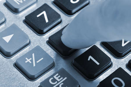The calculator and a hand of the man. Pressing of a key of the calculatorの写真素材