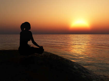 The women in a pose of a lotus. A sunset above oceanの写真素材
