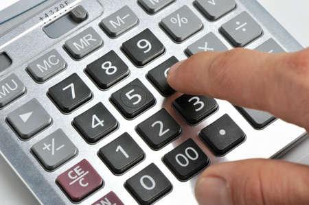 The calculator and a hand of the man. Pressing of a key of the calculator