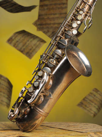 Old saxophone and flying musical notes on a background. The Musical instrument standing on notes with classical music of the beginning of 17 centuriesの写真素材