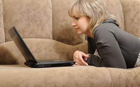 The woman working on laptop at home. House conditions, a sofa.の写真素材