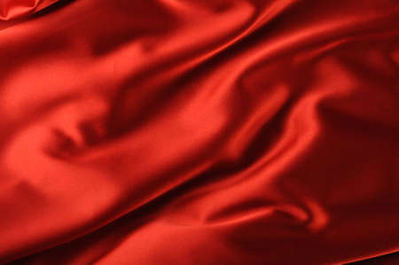 red satin background. A satiny fabric with beautiful light-shadow wavesの写真素材