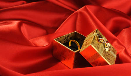Gold boxes with a wedding ring on red silkの写真素材