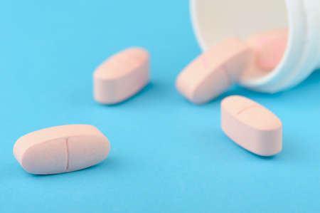 Pink tablets in white plastic packing. A blue backgroundの写真素材