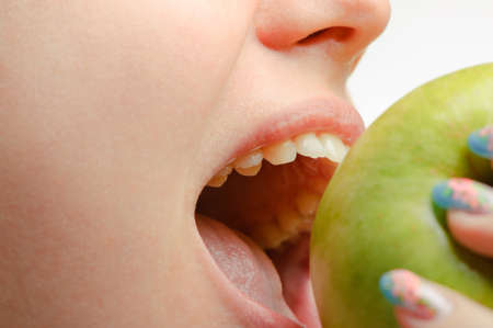 Photo of a female mouth and green apple close upの写真素材