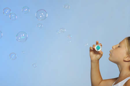 The pretty girl with soap bubbles. A  blue background