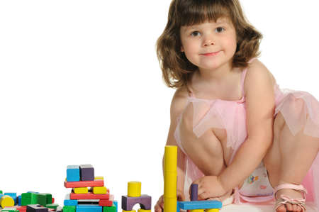 The lovely little girl plays colour wooden cubes. It is isolated on a white backgroundの写真素材