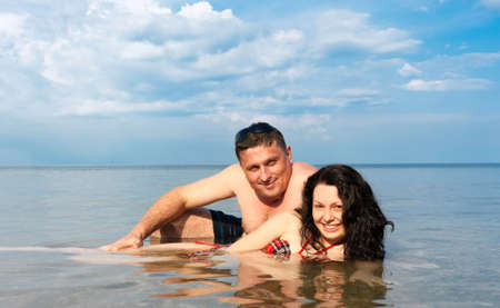 Young pair in the sea. Against the blue sky