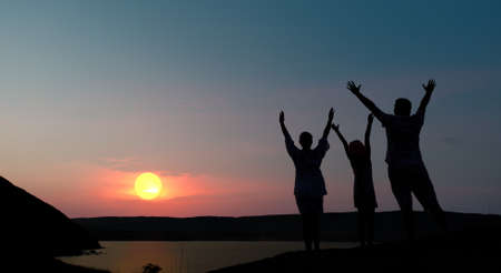 The family from three persons welcomes the sunset sun.の写真素材