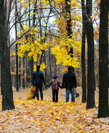 Family in autumn forest. Walk for hands of a happy family from three personsの写真素材