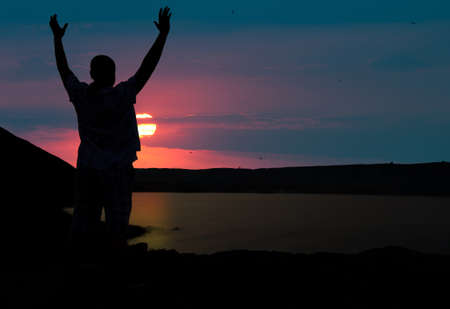 The man welcomes the sunset sun. Upwards the lifted handsの写真素材