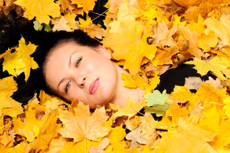 The attractive woman lies in autumn leaf