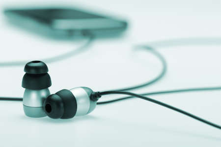 in ear headphone with mobile audio player on bokeh background. Blue tonedの写真素材