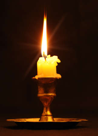 Burning candle. An ancient candlestick, a dark backgroundの写真素材