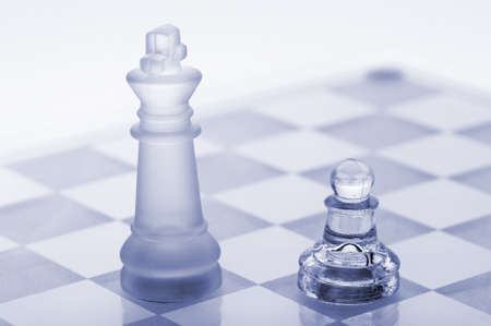 Glass chess. A pawn and a king. Blue toned. It is isolated on a white background.の写真素材