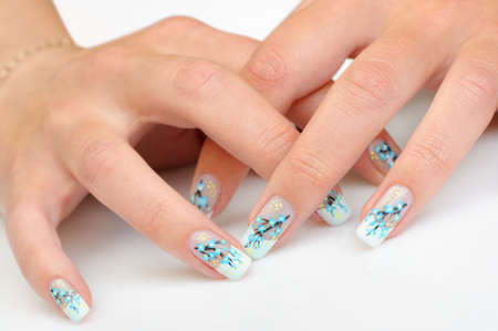 Female hands with manicure close up. Drawing of a branch with blue flowers. It is isolated on a white background.の写真素材